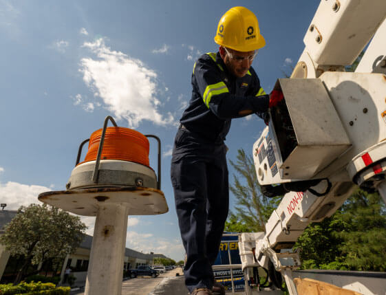 A worker in safety gear operates equipment atop a utility vehicle under a clear sky, embodying the precision and expertise you'd expect from a leading hydraulic and industrial hose service franchise.